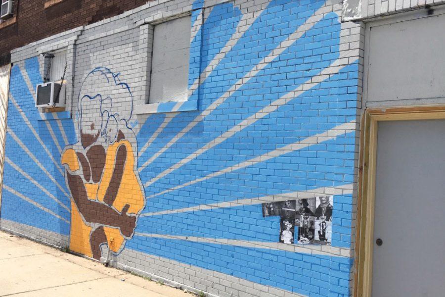 A view of a partially completed mural, with photos of people from the community. 