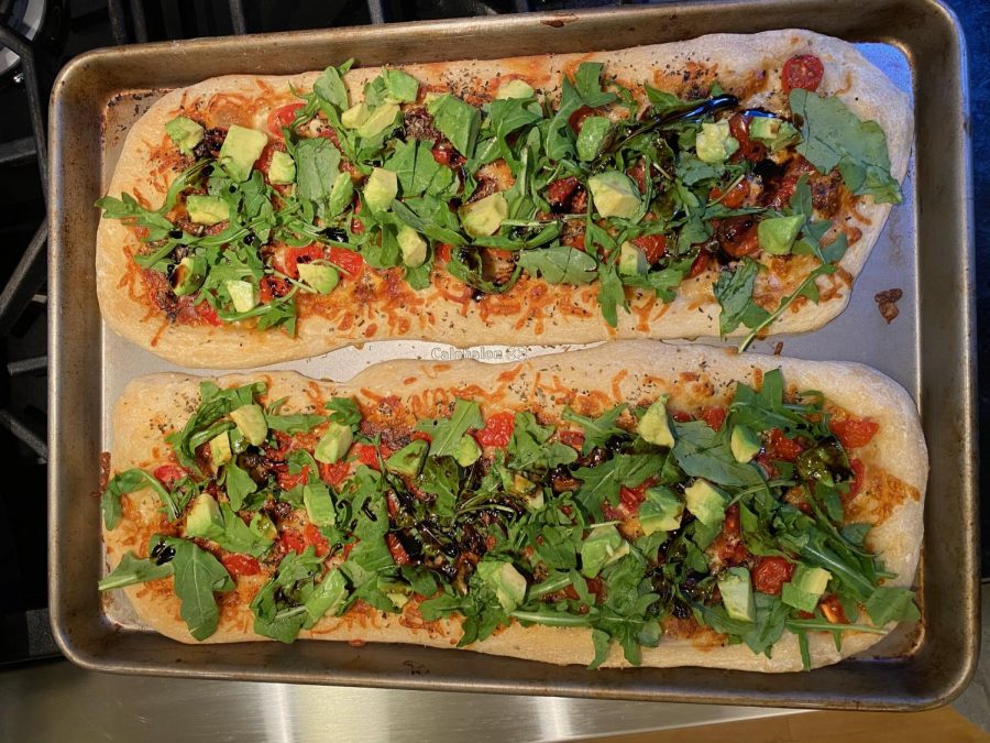 Arugula Caprese flatbread topped with avocado and balsamic glaze.