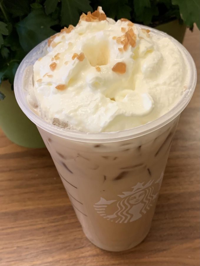 The iced caramel brûlée latte topped with whipped cream in its cup