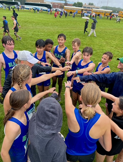 Both girls and boys Cross Country teams huddle together after their muddy race in Decorah IA at Luther College.