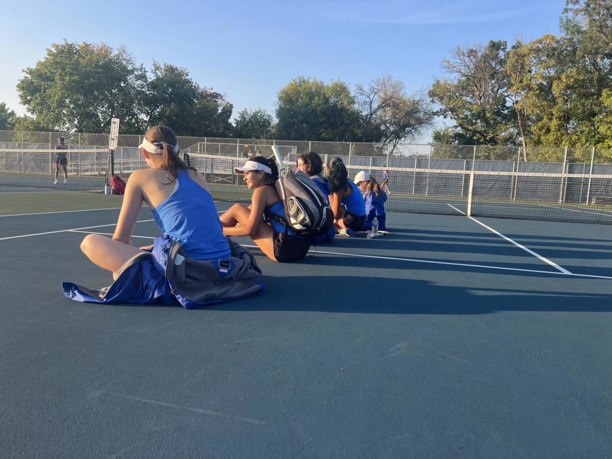 Members+of+the+girls%E2%80%99+tennis+team+watching+and+supporting+their+teammates+after+their+match.