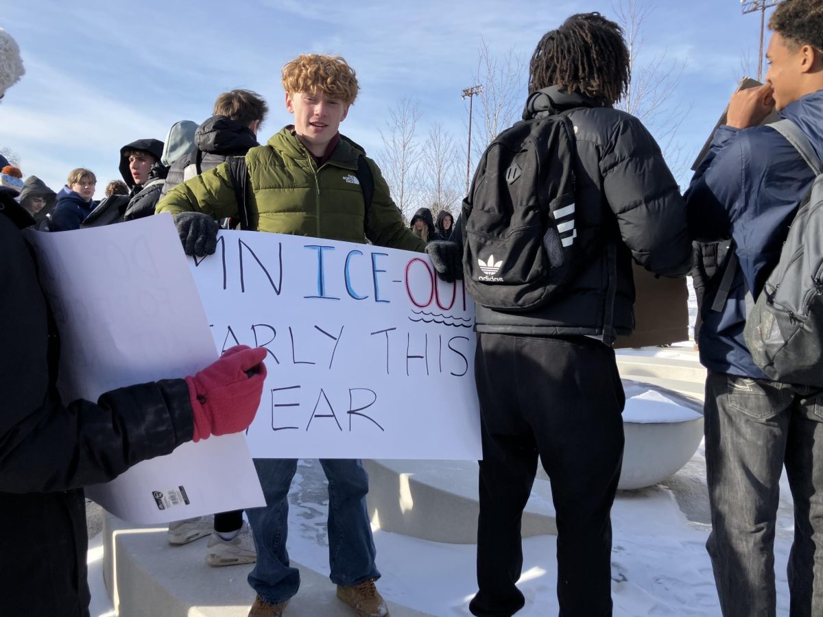 Leo Mithun '28 holds a sign during the Jan. 20 walkout. Other students pictured face student leaders as they spoke out against ICE in the Minneapolis Sculpture Garden.