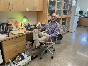 Arnold sits in his office in the science office. This year, h taught Anatomy. Next year, he plans to aid whoever teaches the course.